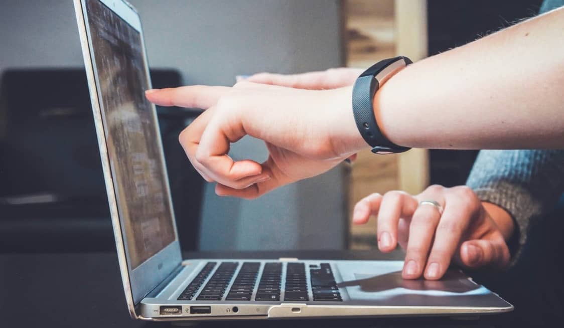 hand pointing at a laptop screen